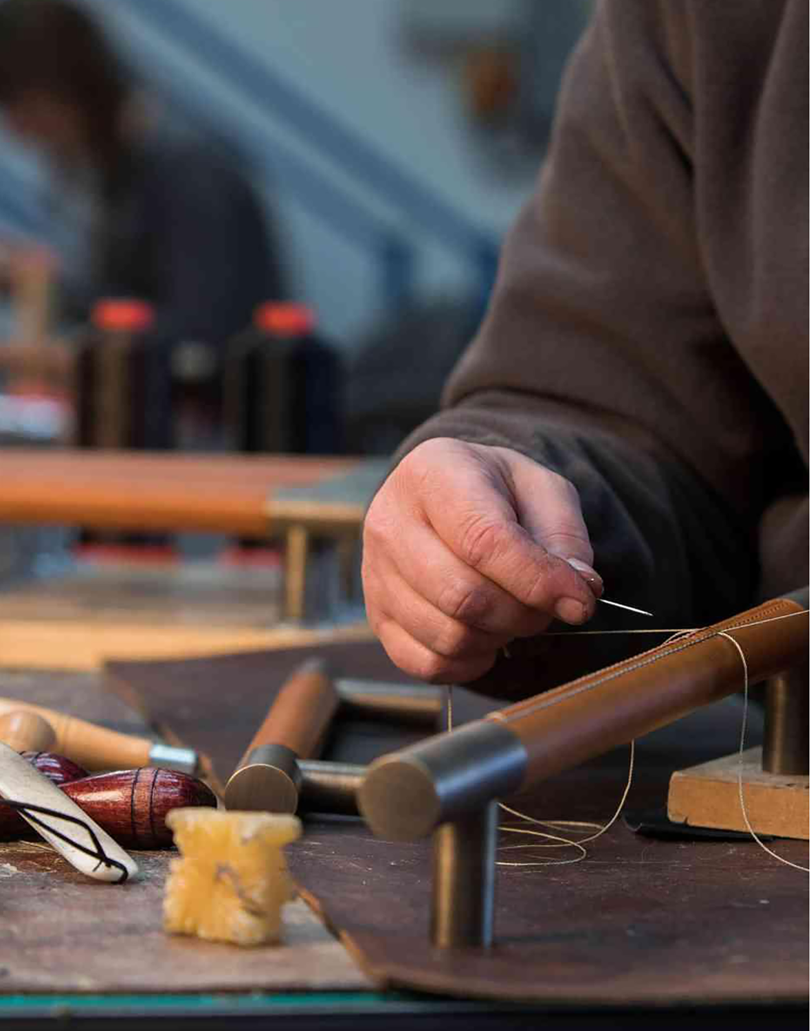 Mann som syr skinn på gripehåndtak til vinrom