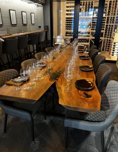 Elegantly set dining table with wine glasses in Vinteknikk's showroom, surrounded by WineGuard glass system and atmospheric lighting.