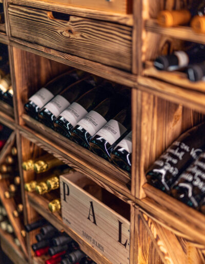 Caverack Half Andino wine rack in charred pine from Vinteknikk, filled with red wine bottles and illuminated with warm LED lighting that highlights the wood's texture and glow.