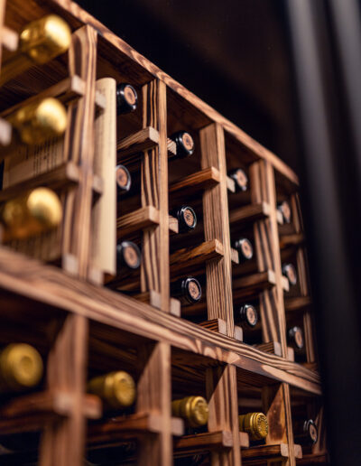 Caverack Half Alda wine shelf in charred pine from Vinteknikk, with warm surface texture and integrated LED lighting that highlights the wine bottles and the material's character.
